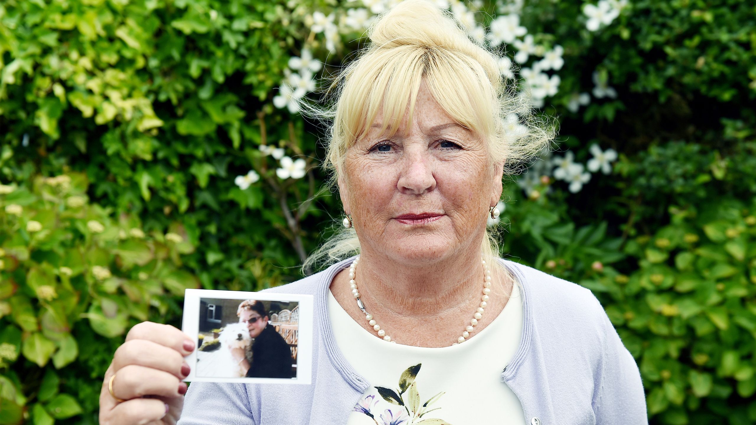 Val Jones, holding up a photo of her sister who died.